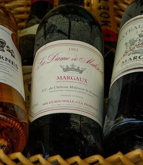 Three Bordeaux Grand Cru wine bottles in a wicker basket